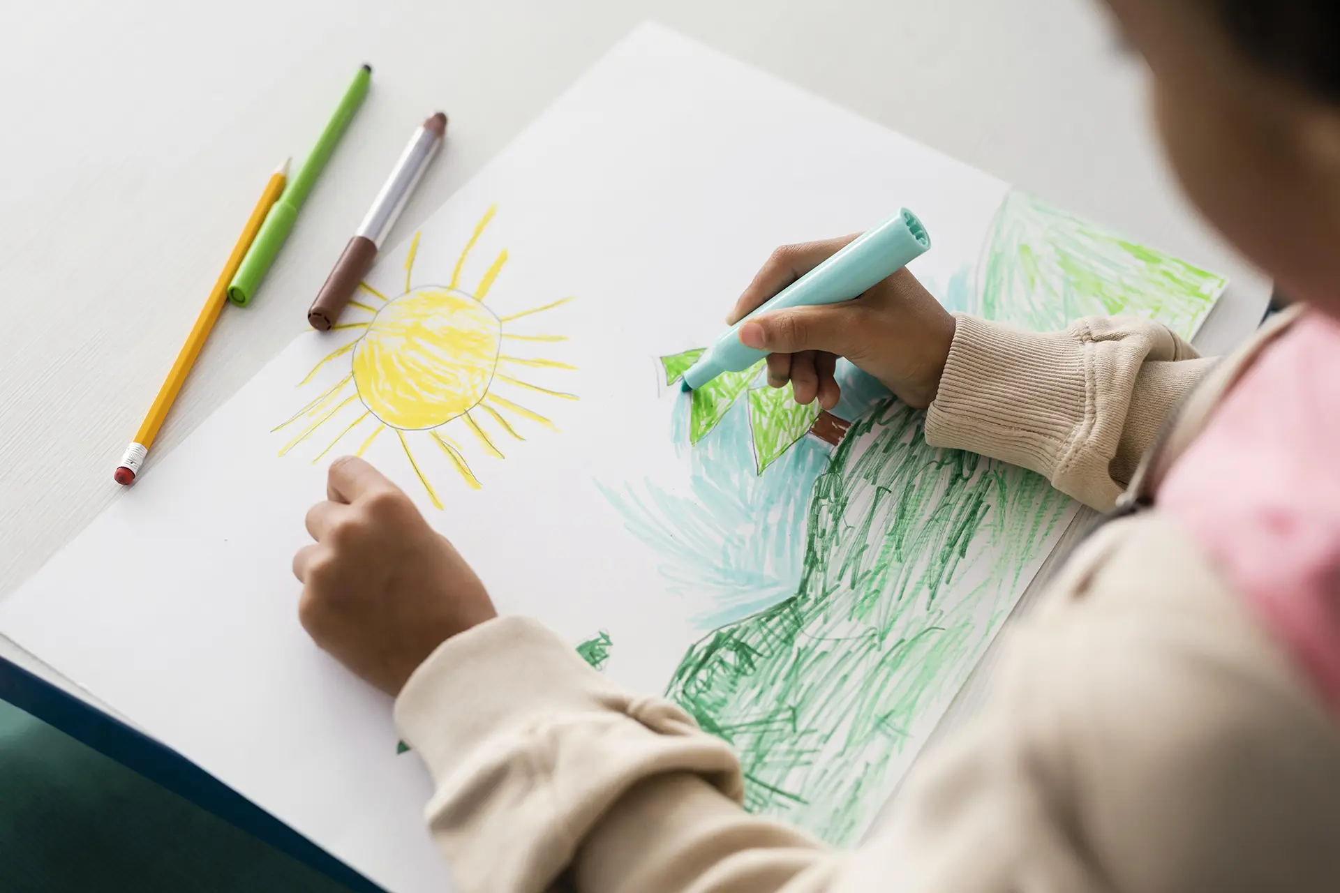 Young student creating a colorful landscape drawing at Art Factory, showcasing our nurturing environment for children's creativity